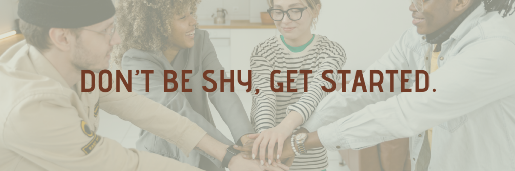 A group of four people in a huddle with their hands in the middle with a text overlay that says don't be shy, get started.