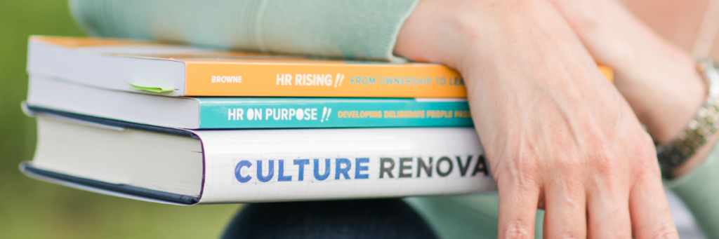 Close up of three HR books sitting on a women's knee with her arms draped over the boooks