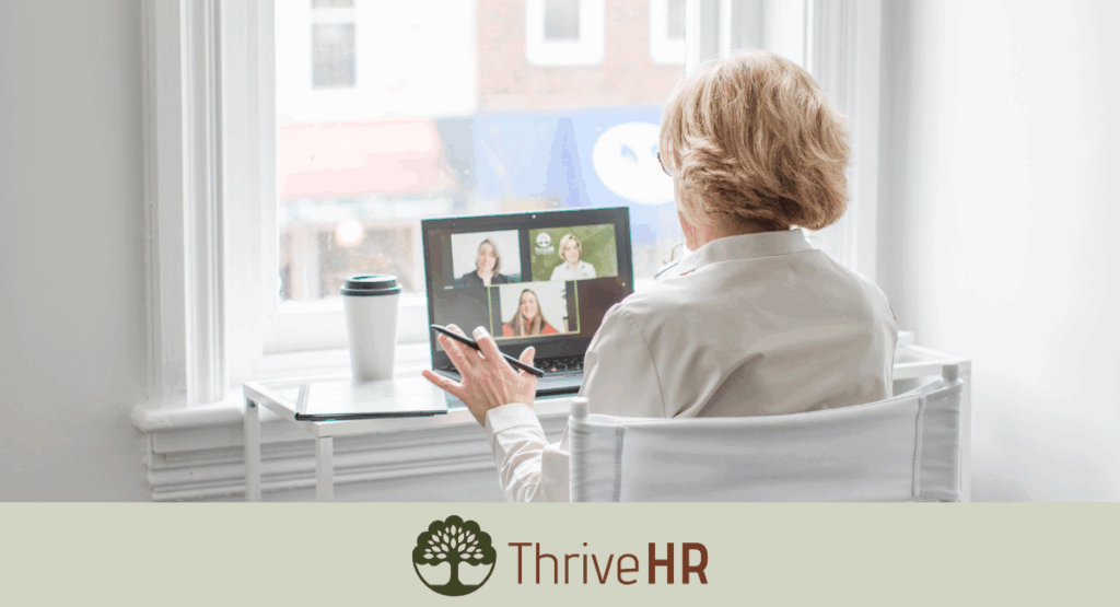 An image of the back of a woman sitting at a desk with the computer in front of her while on a zoom meeting with two other people