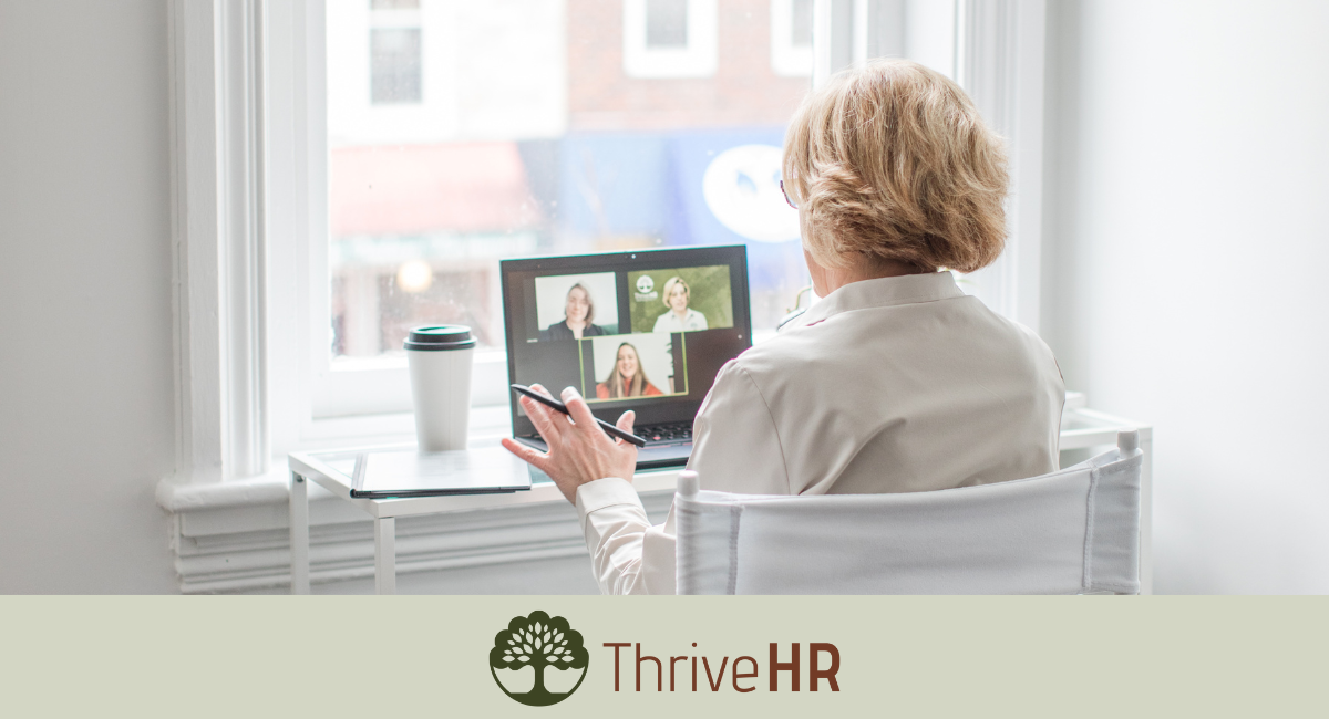An image of the back of a woman sitting at a desk with the computer in front of her while on a zoom meeting with two other people